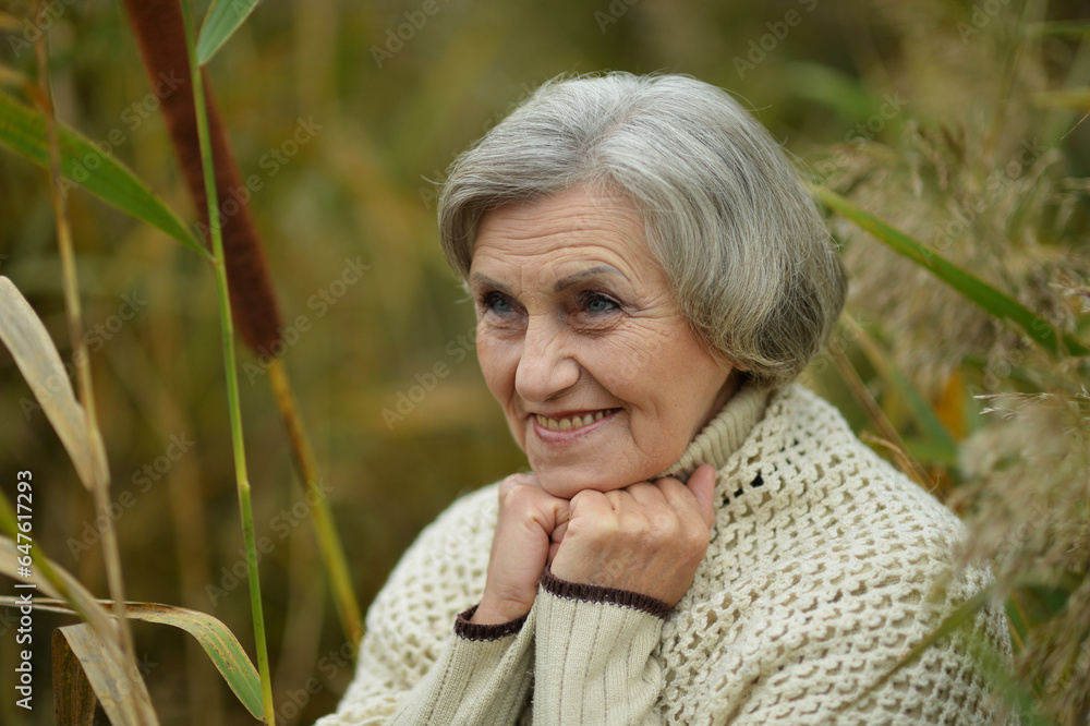 Senior woman walking in the park in autumn Senior woman walking in the park in autumn