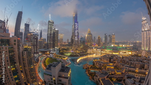 Skyscrapers rising above Dubai downtown day to night timelapse surrounded by modern buildings aerial top view