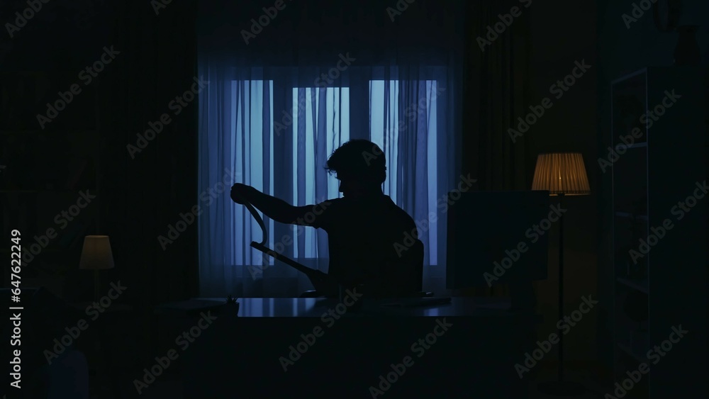Everyday life creative concept. Man sitting at the desk in the dark room and working with paper documents.