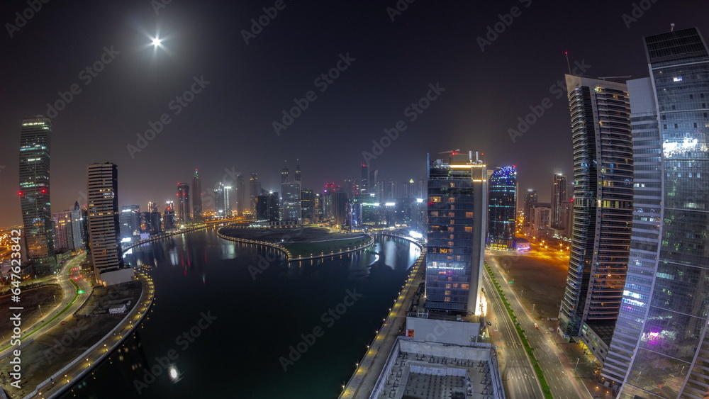 Fototapeta premium Cityscape panorama of skyscrapers in Dubai Business Bay with water canal aerial all night timelapse