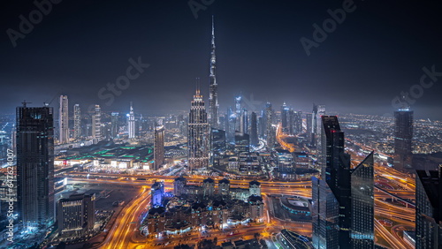 Panorama showing aerial view of tallest towers in Dubai Downtown skyline and highway night timelapse.