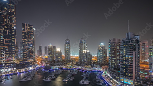 Panorama showing Dubai marina tallest skyscrapers and yachts in harbor aerial night timelapse. © neiezhmakov