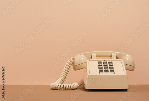 Beige phone with gray buttons on a beige background. Copy space for text. Retro style.