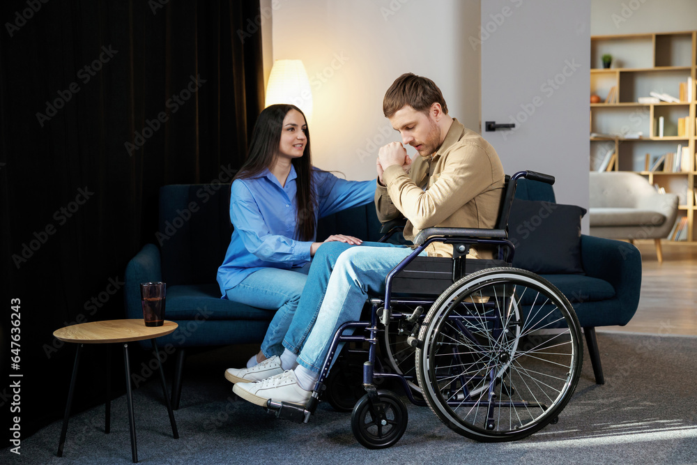 Young man in a wheelchair. Girlfriend comforting her sad boyfriend Young man in a wheelchair. Girlfriend comforting her sad boyfriend
