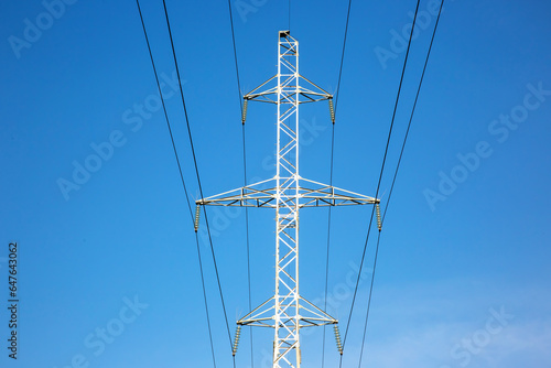 Electrical tower with voltage transmission wires against the background of blue sky. High voltage tower. power line support with wires for electricity transmission. Energy industry.