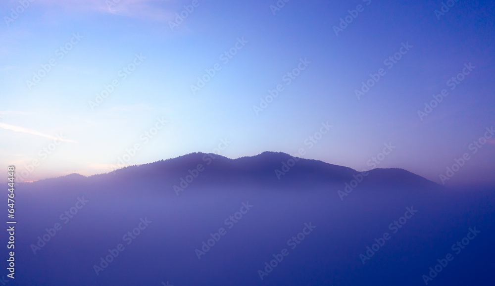 Ethereal Dawn: Silhouetted Mountains in the Mist