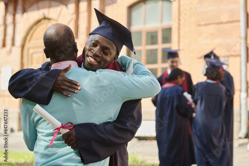 African American father congratulating his son with graduation, they standing outdoors and embracing each other