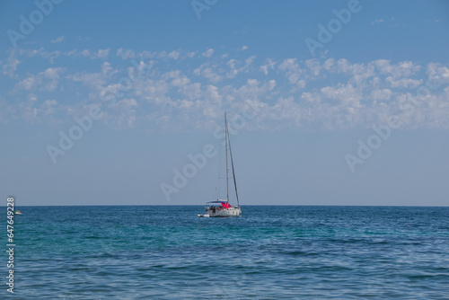 Barco solitario sobre fondo azul y cielo con nubes
