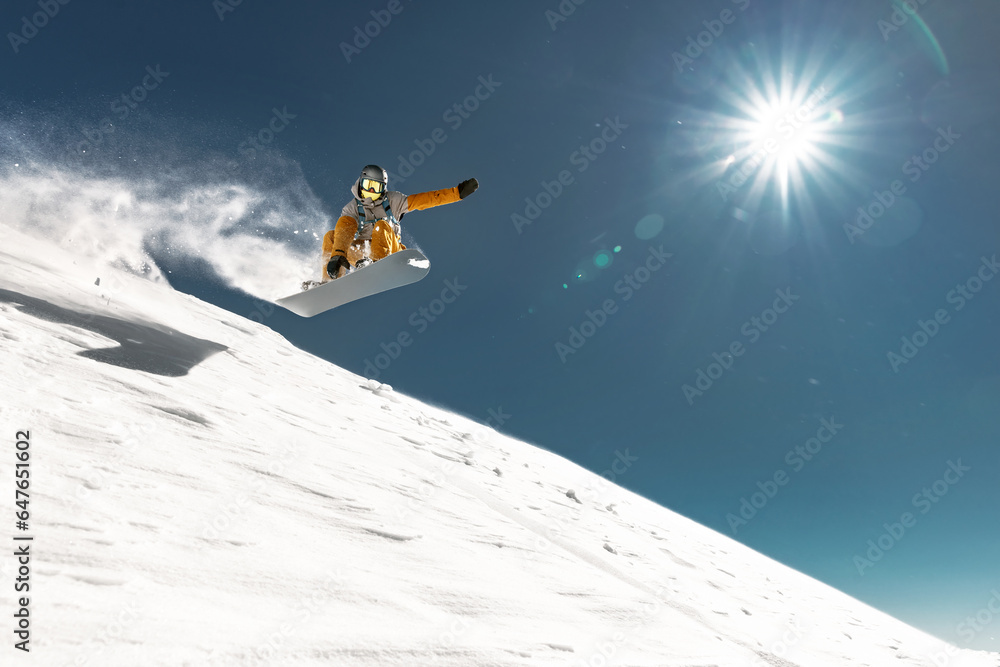 Real young snowboarder jumps and making trick from kicker at off piste ski slope. Winter vacations concept