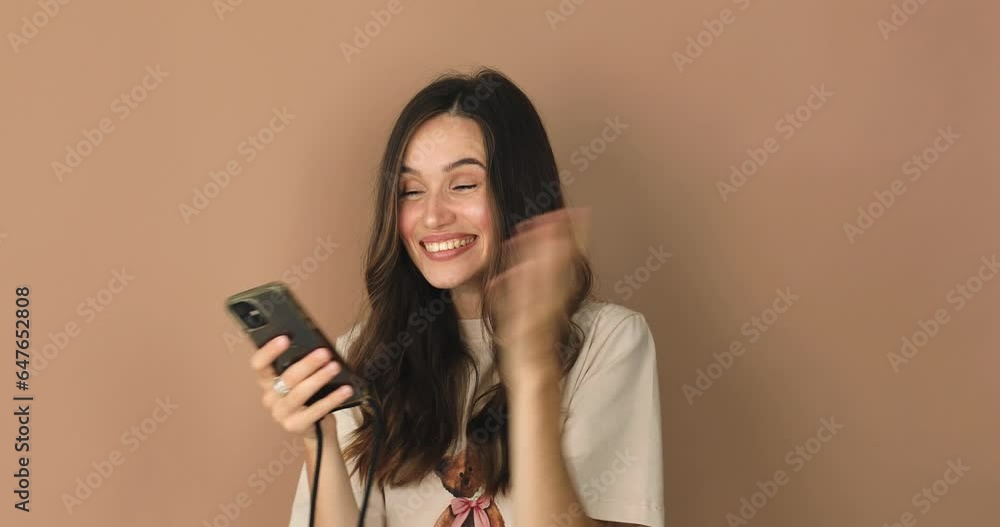 Attractive brunette curly woman look surprised wow hold using mobile cell phone on pink background. Girl look on smartphone and doing winner gesture. Girl just found out great big win news, sales. Attractive brunette curly woman look surprised wow hold using mobile cell phone on pink background. Girl look on smartphone and doing winner gesture. Girl just found out great big win news, sales.