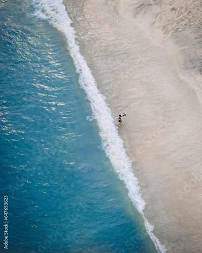 Aerial view of a person with a surfboard along the shoreline at Lantau island, Cheung sha Beach, Hong Kong. photo