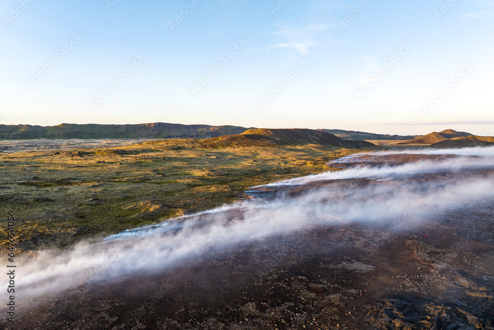 Aerial view of the magma flowing and burning grass across the valley from Litli-Hrutur (Little Ram) Volcano during an eruption on Fagradalsfjall volcanic area in southwest Iceland. Aerial view of the magma flowing and burning grass across the valley from Litli-Hrutur (Little Ram) Volcano during an eruption on Fagradalsfjall volcanic area in southwest Iceland.
