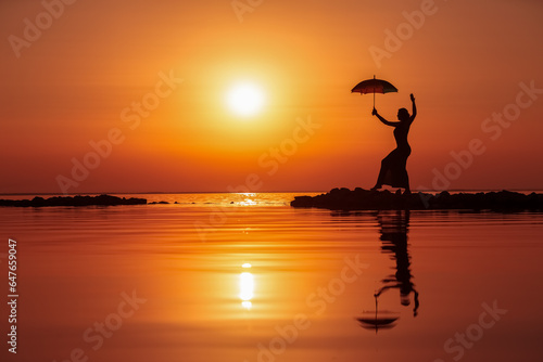 Silhouette of a woman with an umbrella at sunset on the sea