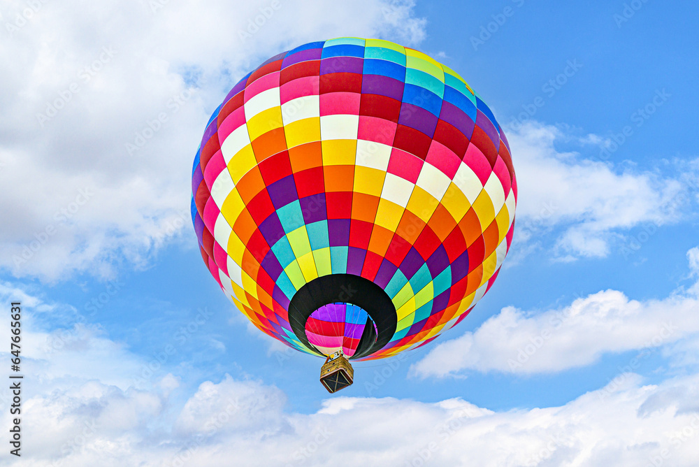 Fototapeta premium Colorful hot air balloon flying over blue sky with white clouds 