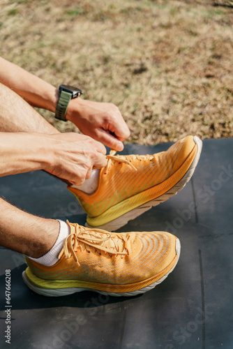 Sports shoes for running yellow. Break the man on the mat adjusts his sneakers. Fitness concept.
