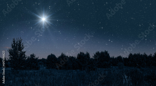 Bright star shines over the manger of christmas of Jesus Christ on blue starry sky
