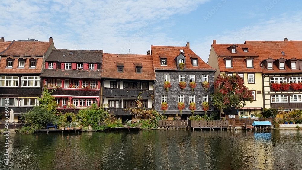 A tranquil scene unfolds along the waterfront, where a row of buildings stands gracefully, reflecting off the gentle waves. Bamberg, Germany