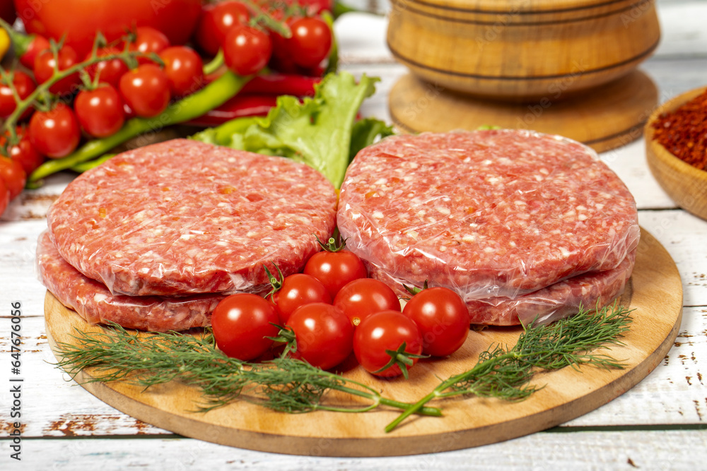 Raw hamburger patties on wood background. Raw veal hamburger patties with herbs and spices. Close up