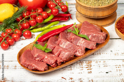 Raw beef tenderloin on wood background. Raw beef tenderloin with herbs and spices