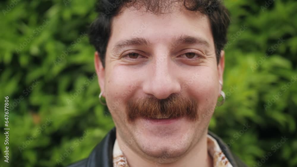 Close up of hispanic stylish man. Portrait of attractive young man with curly hair and moustache wearing piercing looking confident.