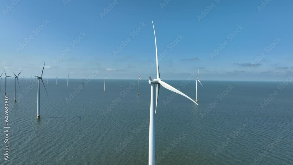Wind turbines with turning blades in an offshore wind farm during springtime seen from above. Wind turbines with turning blades in an offshore wind farm during springtime seen from above.