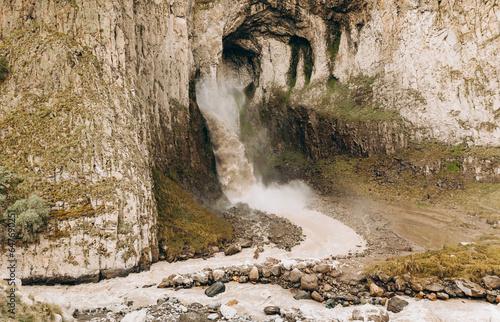 A high, stormy waterfall flowing down the massive rocks of Djily-su. A journey through the mountain beauty of the Caucasus.