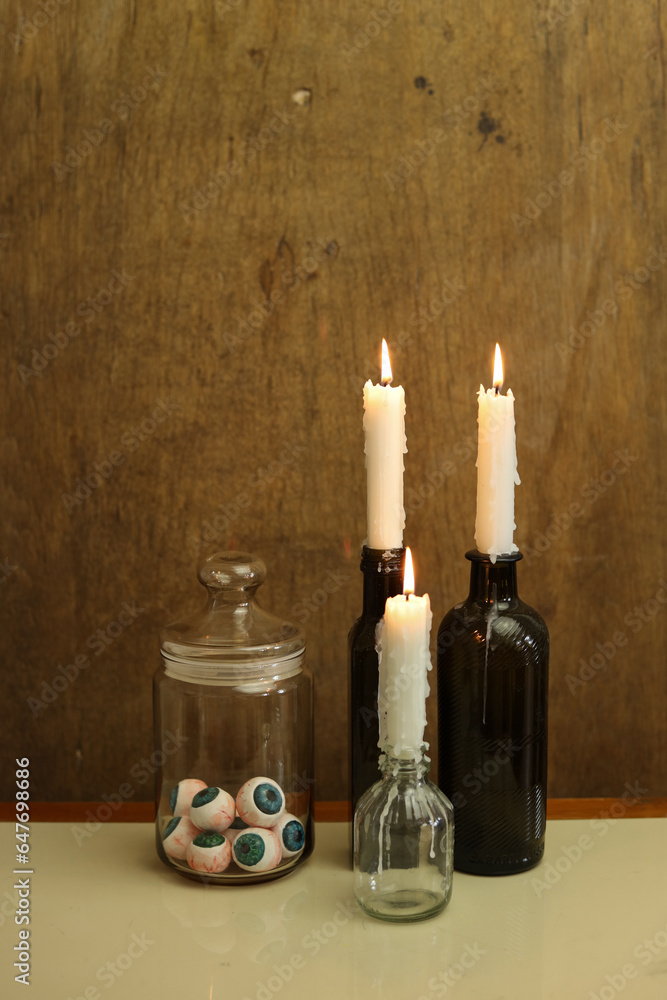 halloween still life with a jar of eyeballs and glowing candles