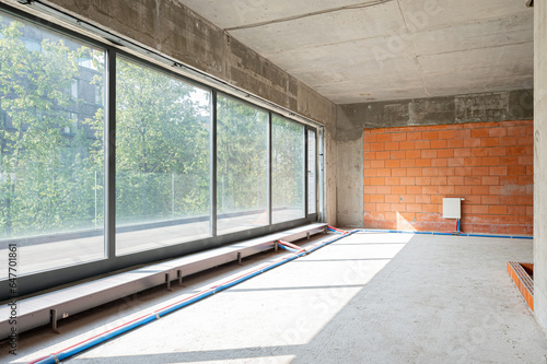 The unfinished room in a residential interior building construction with red brick bare walls and panoramic window.