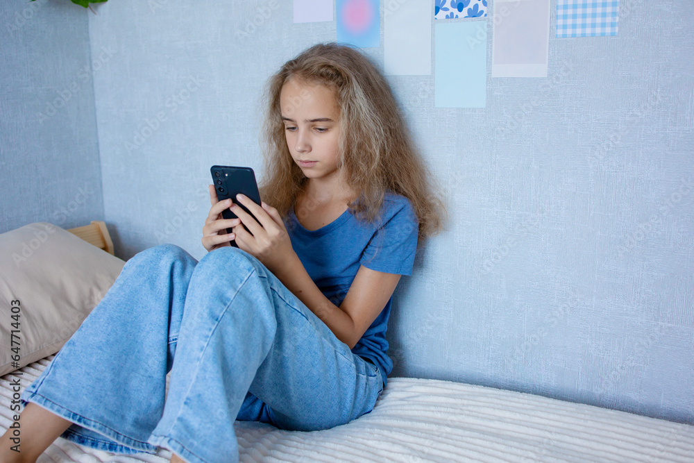 A cute teenage girl communicates via video over the Internet using a smartphone with her friends and classmates. Writes a message or speaks on speakerphone. A cute teenage girl communicates via video over the Internet using a smartphone with her friends and classmates. Writes a message or speaks on speakerphone.