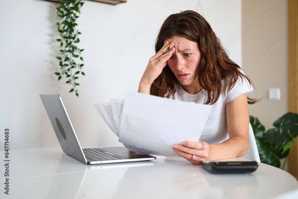 Desperate woman looking at papers working at home Desperate woman looking at papers working at home