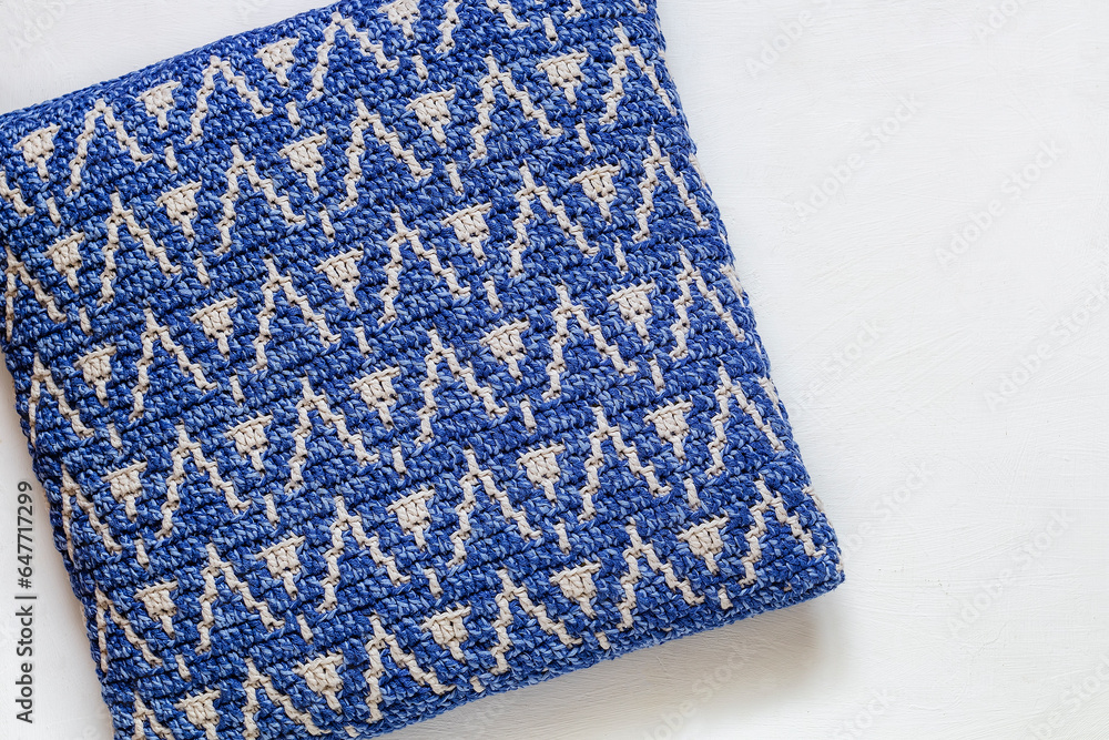 Blue white crochet pillow with abstract pattern on a white background. Top view. Copy space. Blue white crochet pillow with abstract pattern on a white background. Top view. Copy space.