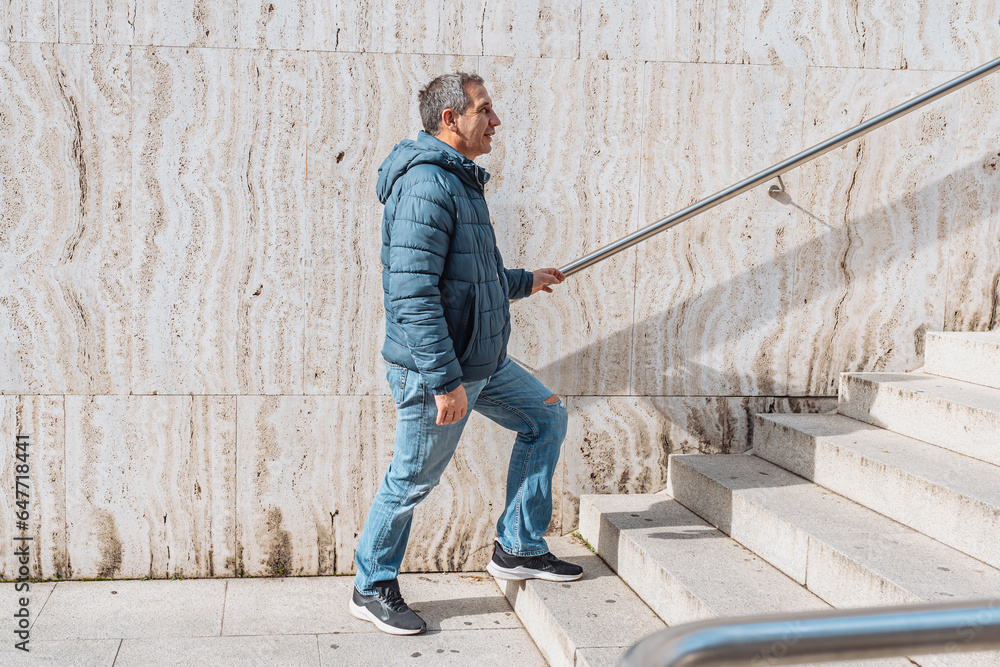 Portrait positive middle-aged man against background marble wall with steps Portrait positive middle-aged man against background marble wall with steps