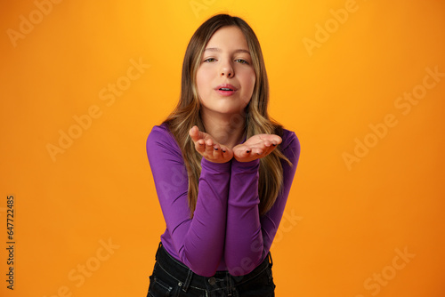 Teen girl blowing a kiss against yellow background