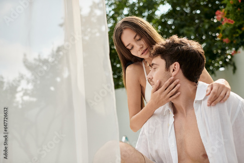 beautiful woman touching cheek of handsome man during summer vacation, couple near beach pavilion © LIGHTFIELD STUDIOS