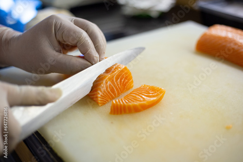 Chef cuts salmon and uses it to make sushi and sashimi on the restaurant.