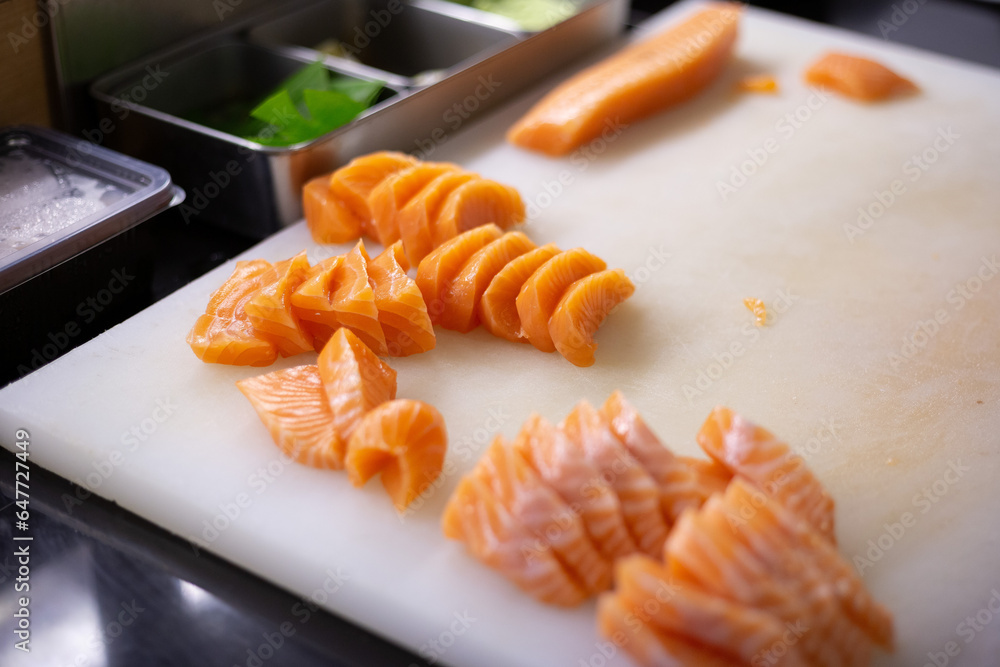 Chef cuts salmon and uses it to make sushi and sashimi on the restaurant. Chef cuts salmon and uses it to make sushi and sashimi on the restaurant.