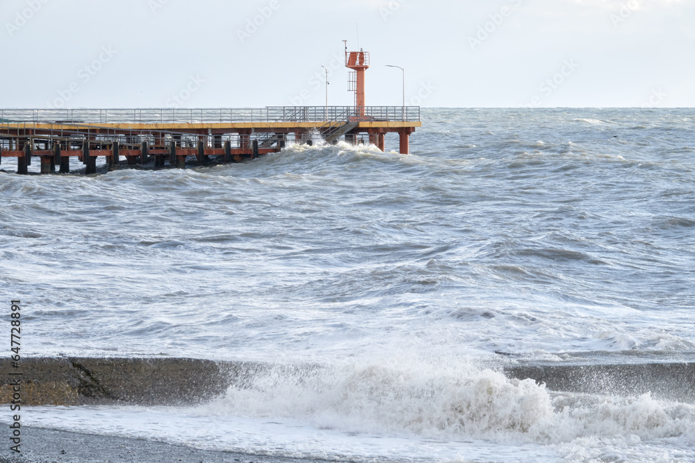 Red lighthouse on the background of the sea. Pier on the embankment. Black Sea, Adler, Russia.