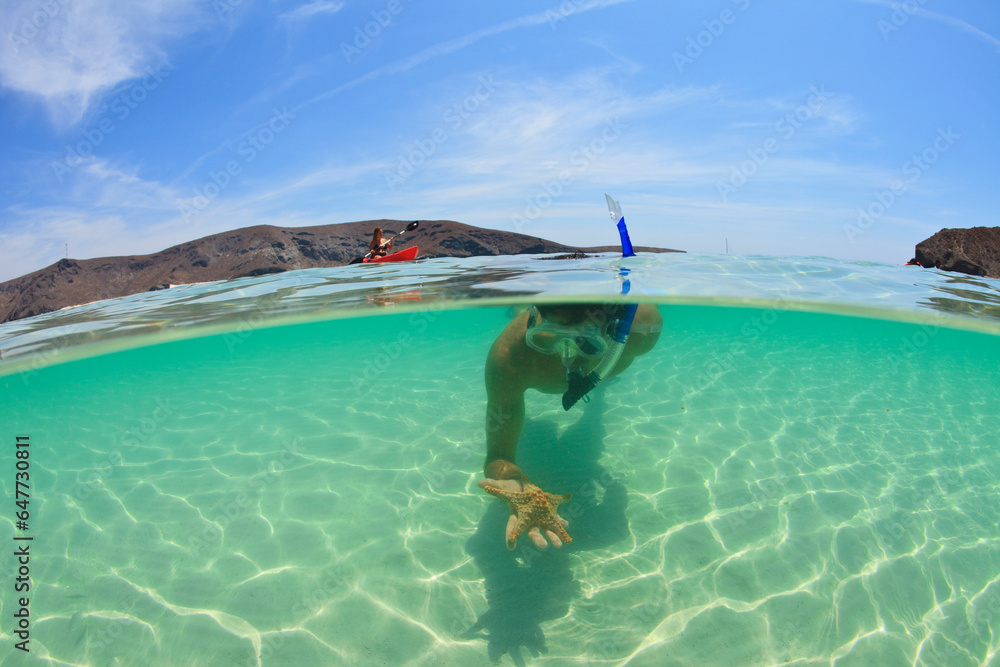 A Young Man Snorkeling Underwater Holding A Starfish In His Hand; La Paz, Baja, California, Sur Mexico A Young Man Snorkeling Underwater Holding A Starfish In His Hand; La Paz, Baja, California, Sur Mexico