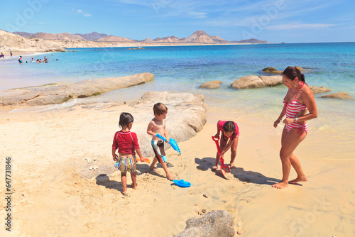A Mother Plays With Her Three Children On A Beach; San Jose Del Cabo, Baja California Sur, Mexico photo