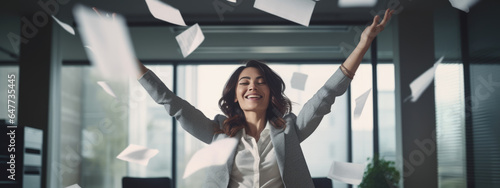 Happy businesswoman throwing papers in the air as a sign of victory and success in her work