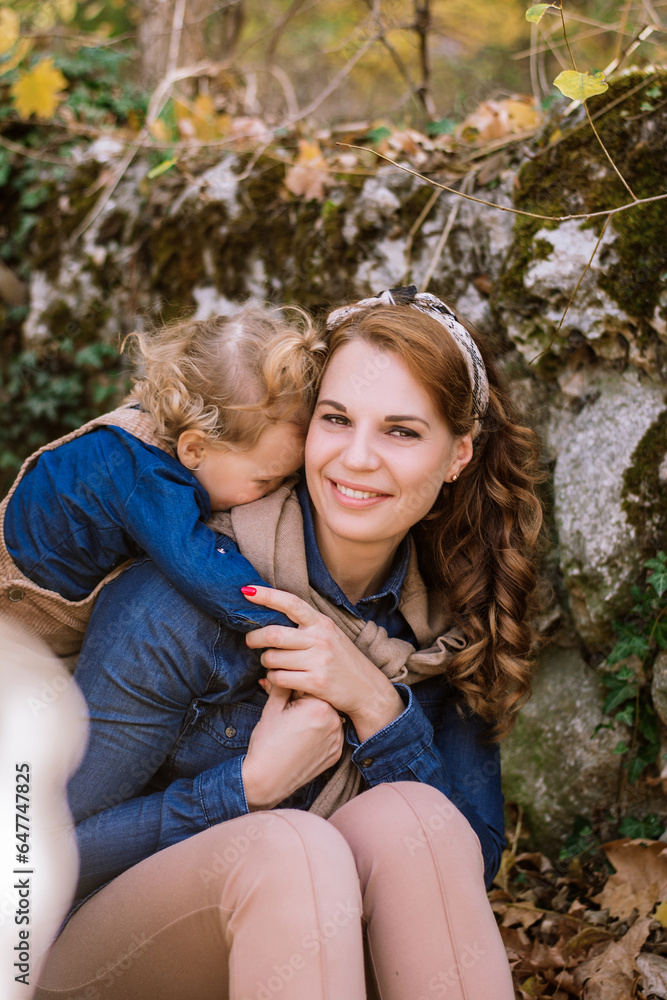 Happy mother 28-35 years old hugging her daughter toddler 1-2 years old. Family, happy childhood, stylish family street look, hugs of people. Concept: family and love. Selective focus on mom's face Happy mother 28-35 years old hugging her daughter toddler 1-2 years old. Family, happy childhood, stylish family street look, hugs of people. Concept: family and love. Selective focus on mom's face