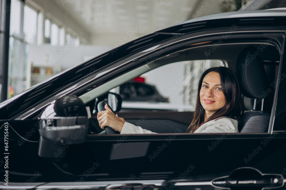 Woman sitting in her new car in a car showroom Woman sitting in her new car in a car showroom