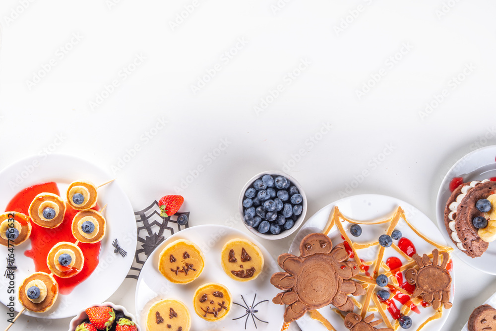 Funny kids breakfast for Halloween. Creative homemade sweet pancakes in form of traditional Halloween monsters and symbols, with fresh berry, chocolate and red syrup