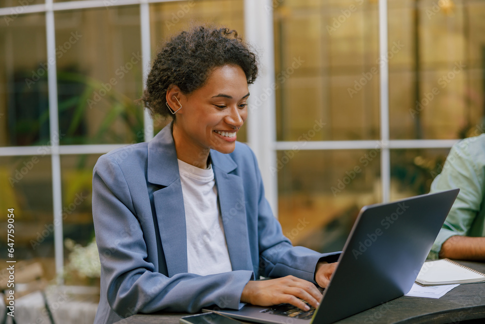 Smiling female sales manager working on laptop on modern office terrace Smiling female sales manager working on laptop on modern office terrace