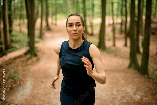 Fit woman with long hair runs in forest trail among trees. Fitness, jogging for health