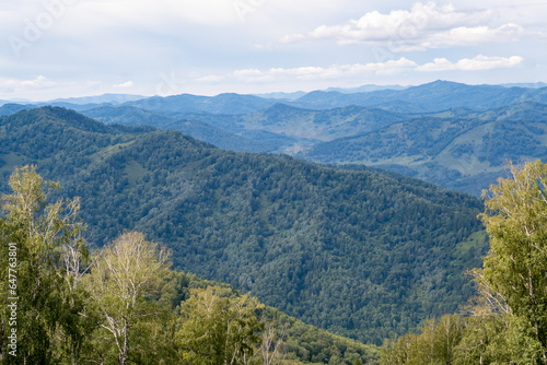 Amazing view of mountains and forest landscape with cloudy skies Altai mountains. Natural green landscapes against the background of clouds, and below the village of Manzherok, Altai Republic, Russia.