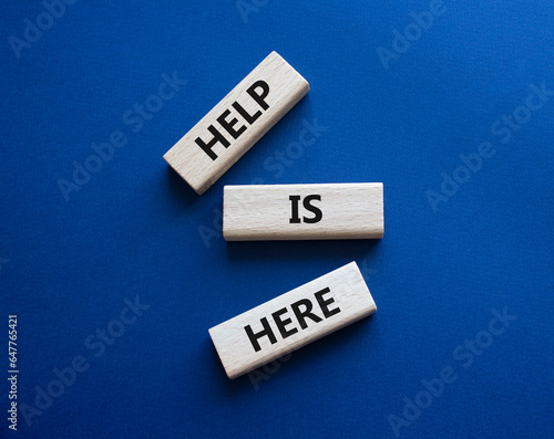 Help is here symbol. Wooden blocks with words Help is here. Beautiful deep blue background. Business and Help is here concept. Copy space.