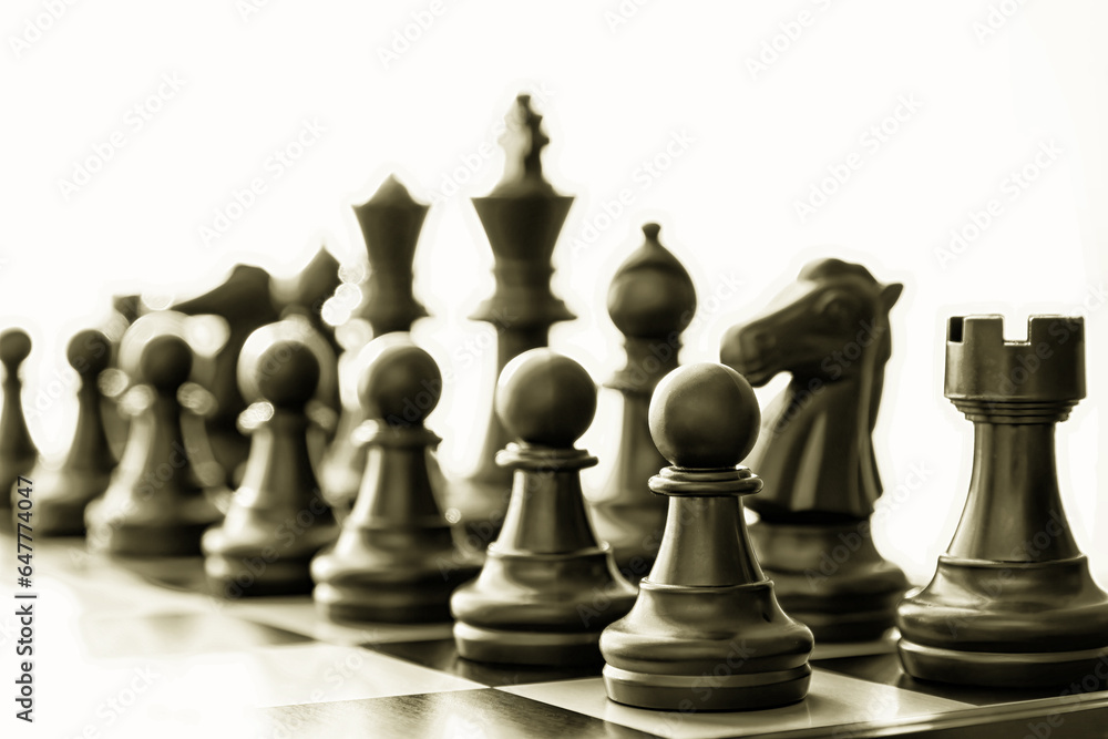 Isolated black chess figures on the chessboard toned with dark gold color. Conceptual chess and leisure activity backgrounds Isolated black chess figures on the chessboard toned with dark gold color. Conceptual chess and leisure activity backgrounds