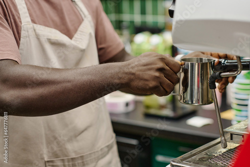 Close-up of African American barista making coffee in cafeteria