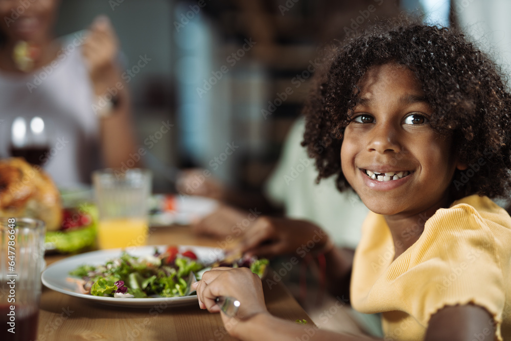 Happy African American girl having dinner with her family at dining table